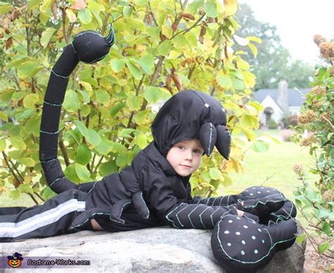 a young boy in a costume laying on top of a rock