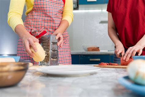 Two Women Are Cooking In The Kitchen Slicing Sausage And Grating