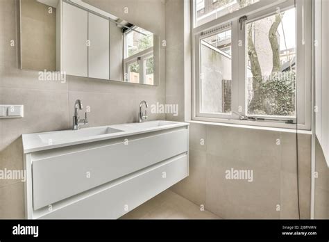 Interior Of Spacious Bathroom With Double Ceramic Sink And Taps On