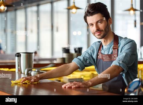 Professional Occupation. Bartender standing wiping counter with rag ...