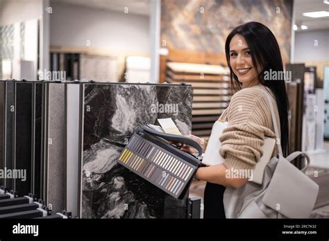Happy Brunette Female Interior Designer Choosing Flooring Tile Color Texture Samples At Store