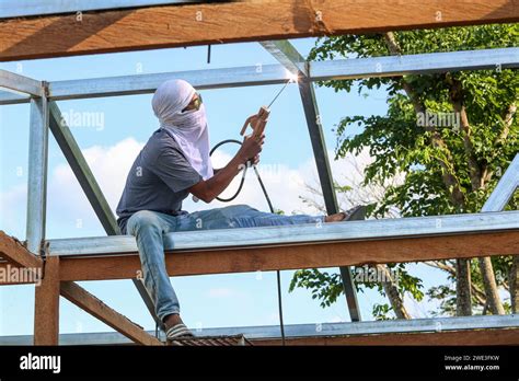 Filipino Construction Worker Welding On Roof Metal Structure Of A Bahay