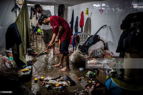 Two Men Try To Remove Water From Their Flooded Store In Lisbon On