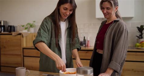 Close Up Of A Brunette Girl Together With Her Mature Mother Cooking In The Kitchen Before