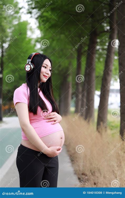 Mujer China Asiática Embarazada Con Vestido De Yoga Escucha Auriculares