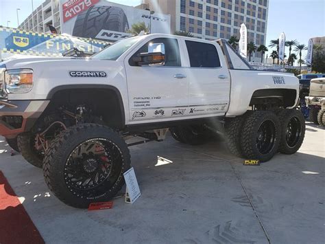 A White Truck Parked On Top Of A Parking Lot Next To Tall Buildings And