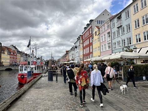 Visitors On Nyhavn Copenhagen Harbor With Classic Boats And Houses