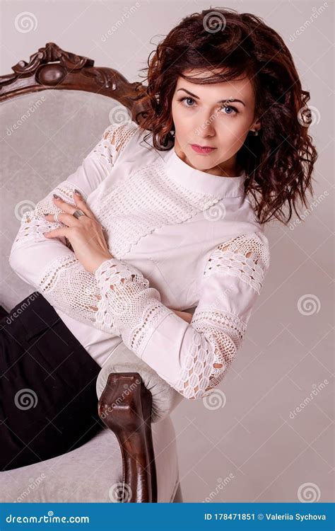 Curly Brunette Leaned On A Beautiful Vintage Armchair Business Elegant Girl In A Blouse And A