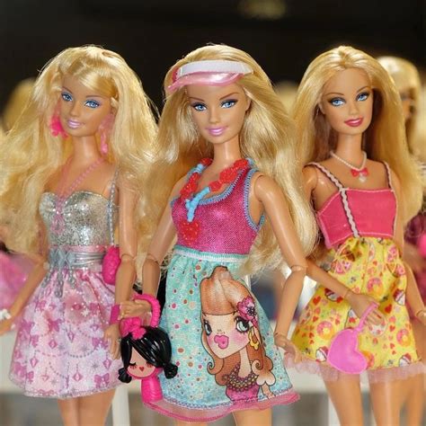 Three Barbie Dolls Standing Next To Each Other