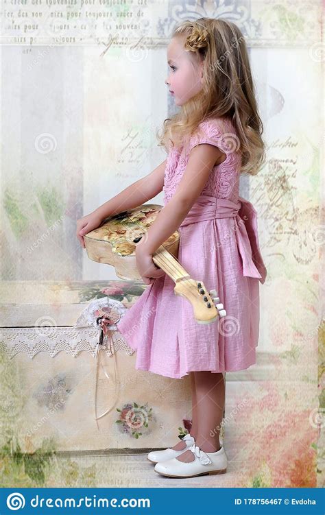 Jolie Petite Fille Blonde En Robe Rose Avec Des Boucles Avec Une