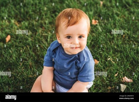 Outdoor Portrait Of Adorable Redheaded Baby Boy Playing In Summer Parc