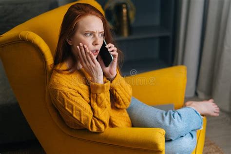 Shocked Excited Young Woman Talking On Smartphone Sitting In Yellow