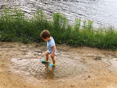 Premium Photo Full Length Of Boy Standing In Puddle By Lake