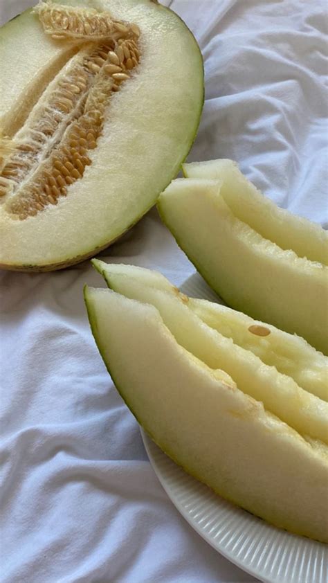 A Melon Cut In Half On A White Plate Next To Another Piece Of Melon