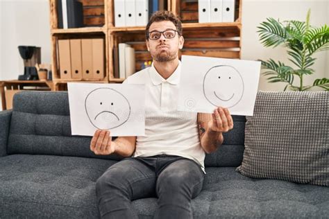 Young Hispanic Man Working On Depression Holding Sad To Happy Emotion