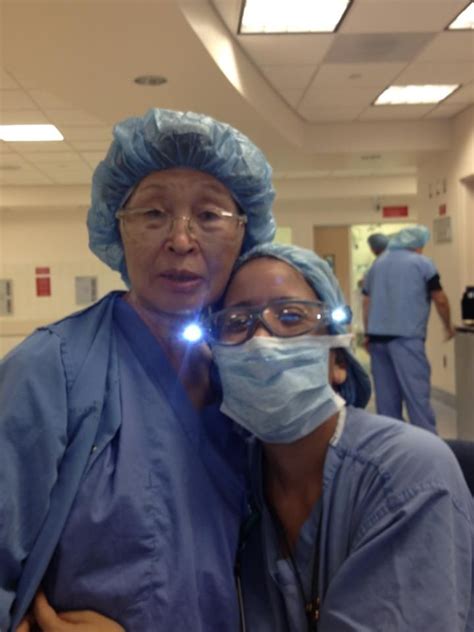 Two Doctors In Scrubs And Masks Pose For A Photo With Their Lights Turned On