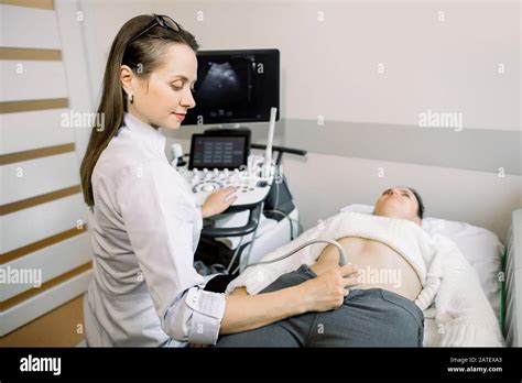 Pretty Female Doctor Operating Modern Ultrasound Scanner While