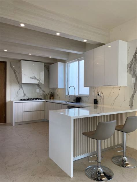 A Kitchen With Two Bar Stools Next To An Island In The Middle Of It