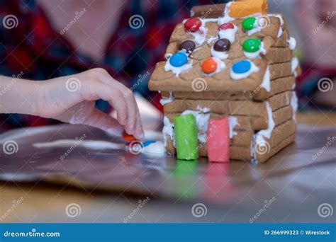 Tiny Hands Decorate A Gingerbread House At Christmas Stock Image