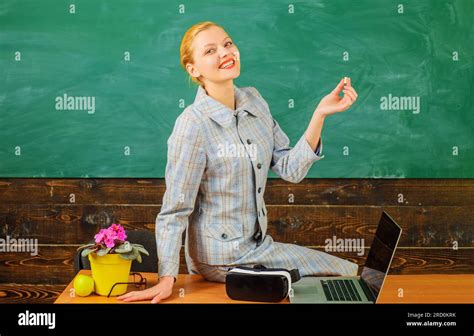 Smiling Female Teacher With Chalk In Front Of Chalkboard At Classroom