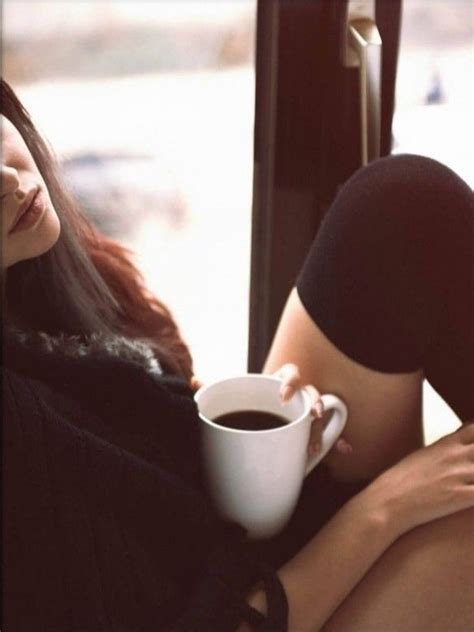 A Woman Holding A Cup Of Coffee While Sitting On A Bus With Her Legs