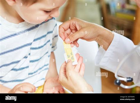 Child Gets A Plaster On A Wound On The Arm From The Pediatrician After