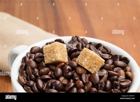 Heap Of Coffee Beans In Cup With Cane Sugar On Brown Wood Table Stock