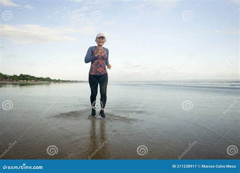 Fit And Attractive Mature Woman With Grey Hair Doing Beach Workout On Her 50s Running On The