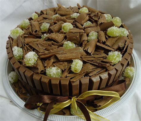 A Chocolate Cake With White And Green Toppings On A Plate Next To A