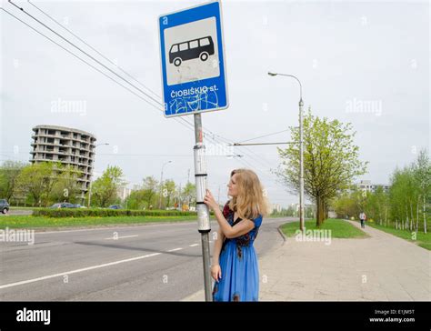 junge blonde Frau an der Bushaltestelle mit Bus Pol Tags fahren Zeitpläne Stockfotografie Alamy