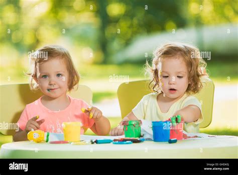 Two Year Old Girls Painting With Poster Paintings Together Against