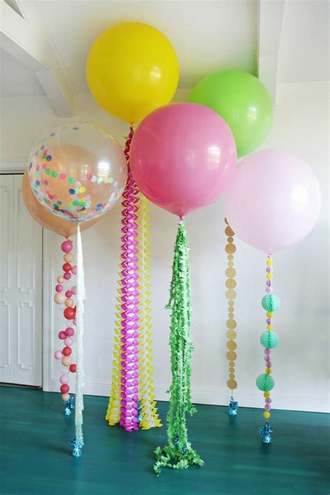 balloons and streamers are hanging from the ceiling in a room with green flooring