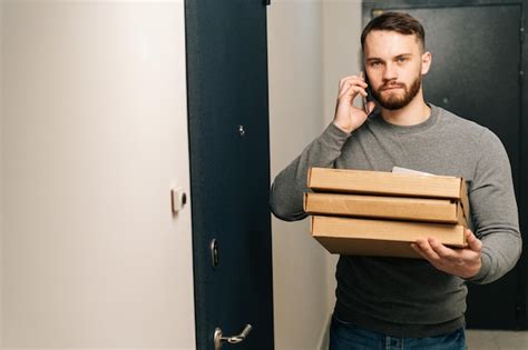 Premium Photo Handsome Delivery Man Standing By Door Of Customer Apartment With Boxes Of Hot