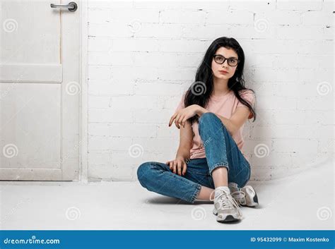 Portrait Of Smart Beautiful Brunette Girl In Eyeglasses With Natural Make Up Sitting Near White