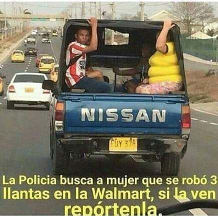 Two People Sitting In The Back Of A Pick Up Truck Driving Down A Street