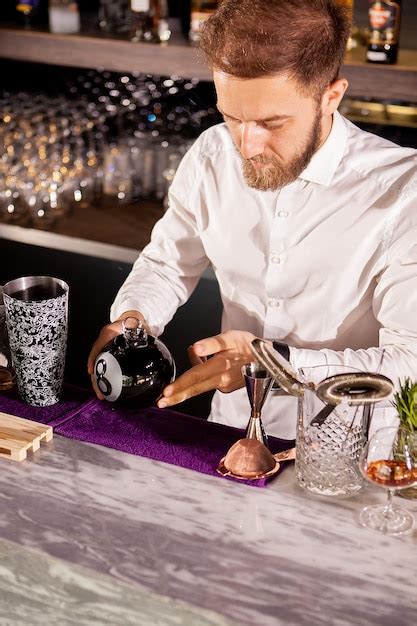 El camarero está haciendo cócteles en la barra del bar en el salón