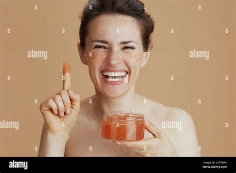 Happy Modern 40 Years Old Woman With Face Scrub Isolated On Beige