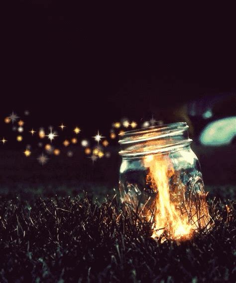 A Glass Jar Sitting On Top Of A Grass Covered Field Next To A Fire Pit