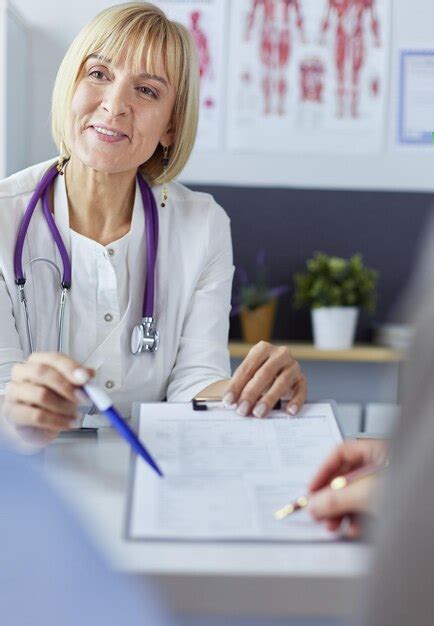 Médico y paciente examinando un archivo con registros médicos ella