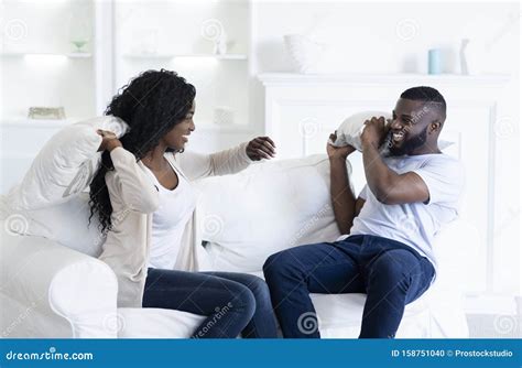 Playful Black Couple Fighting By Pillows Having Fun At Home Stock