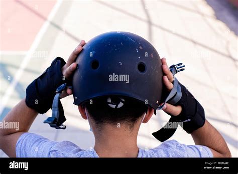 Close Up From Behind Of A Preteen Putting On His Helmet Getting Ready