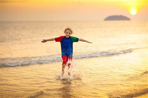 Niños Jugando En La Playa Del Océano Niño Al Atardecer Imagen De