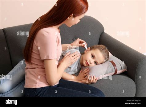 Mother Dripping Medication Into Daughters Ear In Living Room Stock