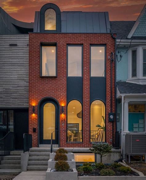 A Red Brick House With Large Windows And Stairs Leading Up To The Front