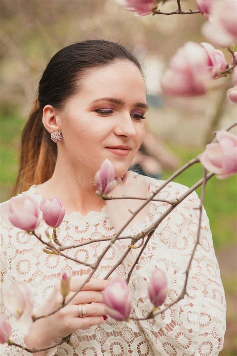 Pretty Brunette Model With Nude Makeup Wearing Lace Blouse Posing Near The Blooming Magnolia