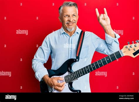 Middle Age Grey Haired Man Playing Electric Guitar Doing Rock Sign