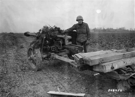 Американский солдат у брошенной немецкой 75-мм противотанковой пушки ...