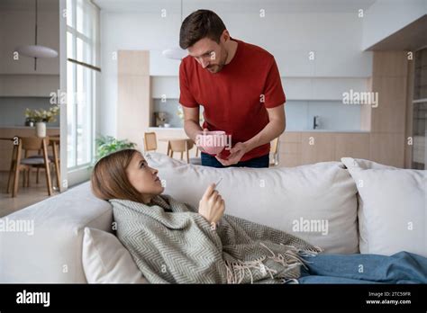 Loving Husband Holding Cup Of Hot Tea Made For Sick Wife Having Influenza Virus Covid Fever