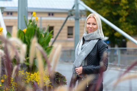 Belle jeune femme blonde contre le bâtiment en brique urbaine avec des arbustes en fleurs et des