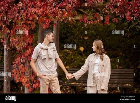 Young Couple In Love Walking In The Autumn Park Holding Hands Looking